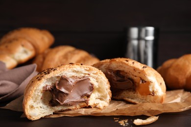 Photo of Fresh croissants with chocolate on wooden table, closeup. Space for text