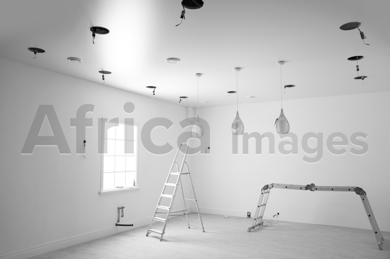 Photo of Empty room with stretch ceiling and ladders