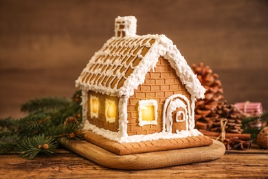 Photo of Beautiful gingerbread house decorated with icing on wooden table