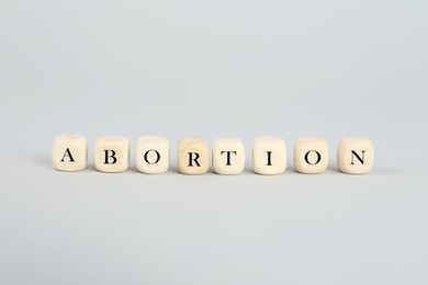 Word Abortion made of wooden cubes on light grey background
