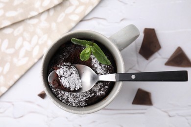 Photo of Tasty chocolate mug pie with mint and spoon on white textured table, flat lay. Microwave cake recipe