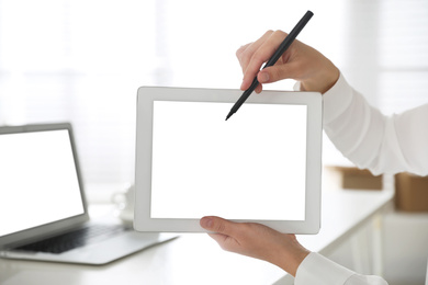 Woman pointing at modern tablet with blank screen in office, closeup