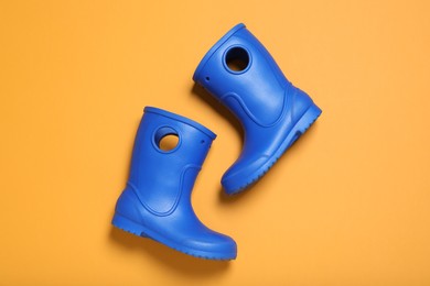 Bright blue rubber boots on orange background, top view