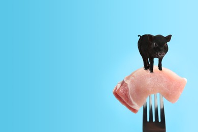 Sample of lab grown pork and small pig on fork against light blue background, space for text. Cultured meat concept 
