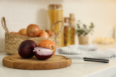 Fresh cut and whole onions on countertop in modern kitchen, closeup