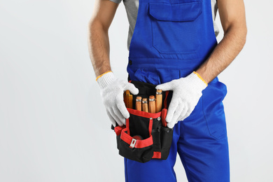 Photo of Carpenter with tool belt on light background, closeup