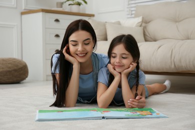 Young mother and her daughter reading book at home