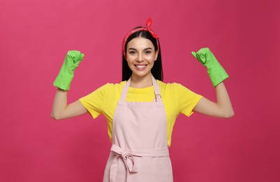 Young housewife wearing rubber gloves on pink background