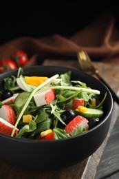 Photo of Tasty crab stick salad on wooden board, closeup
