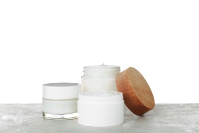 Jars of hand cream on gray table against white background