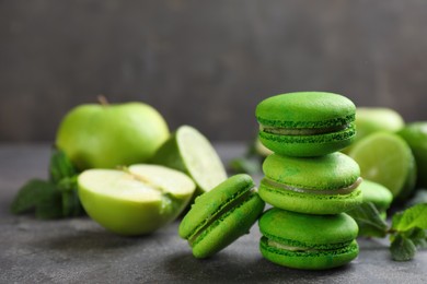 Delicious green macarons, fresh fruits and mint on grey table. Space for text