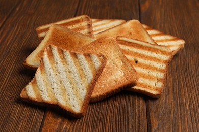 Slices of tasty toasted bread on wooden table