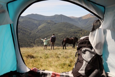 Couple and horse in mountains, view from camping tent