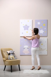 Photo of Decorator hanging picture on pink wall. Children's room interior design