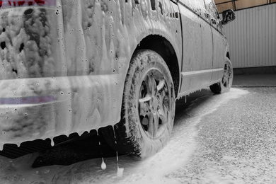 Modern automobile covered with foam at car wash, closeup