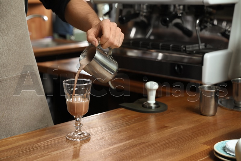 Barista pouring coffee into glass at bar counter, closeup. Space for text