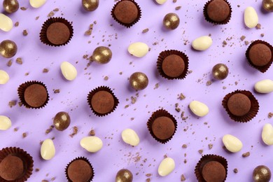 Photo of Different delicious chocolate candies on lilac background, flat lay