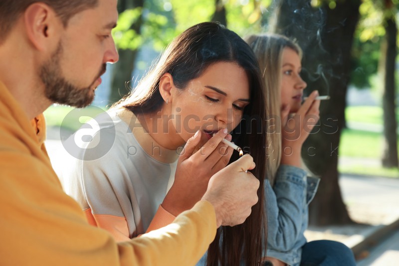 People smoking cigarettes outdoors on sunny day