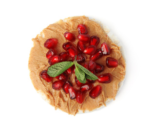 Puffed rice cake with peanut butter, pomegranate seeds and mint isolated on white, top view