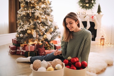 Beautiful woman decorating Christmas tree at home