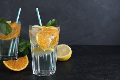 Photo of Delicious orange lemonade with soda water and mint on black table, space for text. Fresh summer cocktail
