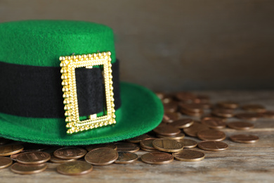 Green leprechaun hat and gold coins on wooden table, space for text. St. Patrick's Day celebration
