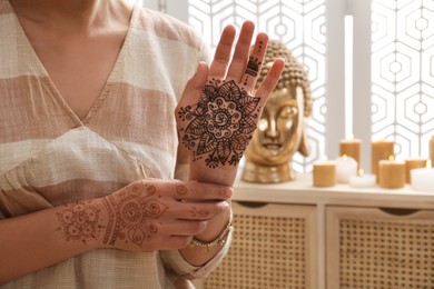 Woman with henna tattoo on hands indoors, closeup. Traditional mehndi ornament