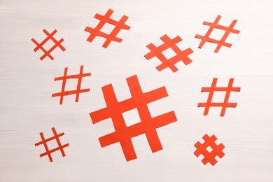 Red paper cutout symbols of hashtag on white wooden background, flat lay