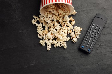 Modern tv remote control and popcorn on black table, flat lay