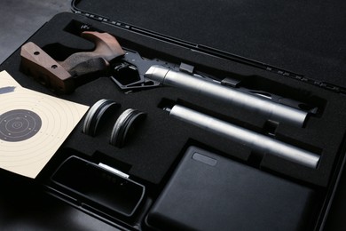 Case with sport pistol and accessories on black table. Professional gun