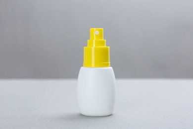 Bottle with insect repellent spray on grey background