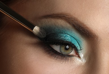 Applying eye shadow onto woman's face, closeup. Beautiful evening makeup