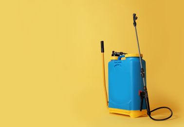 Manual insecticide sprayer on yellow background, space for text. Pest control