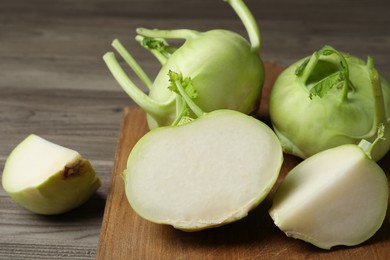 Whole and cut kohlrabi plants on wooden table, closeup