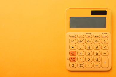 Calculator on orange background, top view with space for text. Tax accounting concept