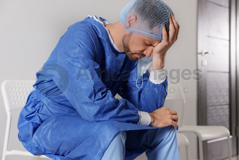 Photo of Exhausted doctor sitting on chair in hospital corridor
