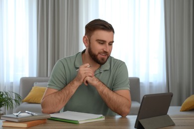 Young man watching online webinar at table indoors