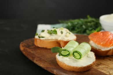 Photo of Delicious sandwiches with cream cheese and other ingredients on wooden board