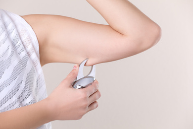 Young woman measuring body fat with caliper on beige background, closeup. Nutritionist's tool