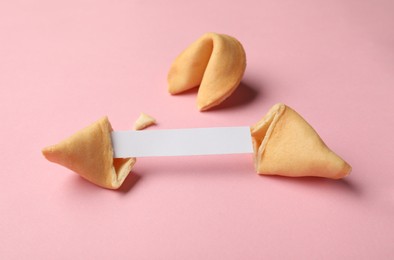 Photo of Tasty fortune cookies with predictions on pink background. Space for text