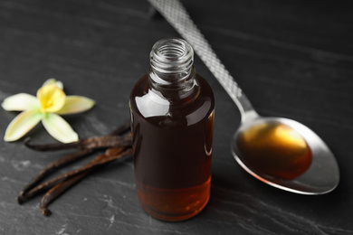 Aromatic homemade vanilla extract on black table, closeup