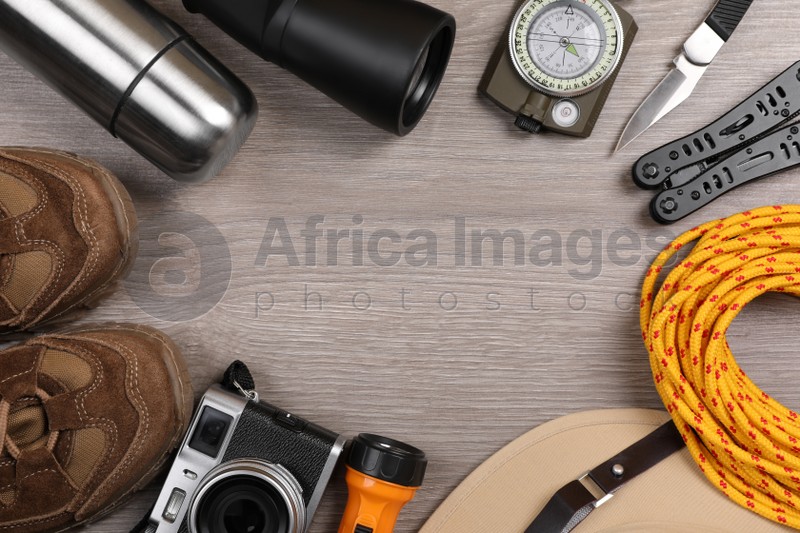 Frame of different camping equipment on wooden background, flat lay. Space for text