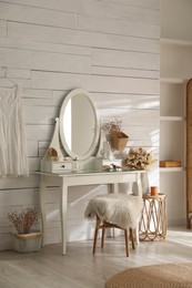 Wooden dressing table with decorative elements and makeup products in room. Interior design