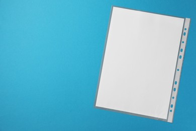 Photo of Punched pocket with paper sheet on light blue background, top view. Space for text