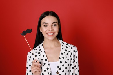 Photo of Happy woman with fake mustache on red background