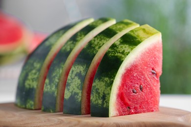 Photo of Slices of delicious ripe watermelon on wooden board indoors, closeup