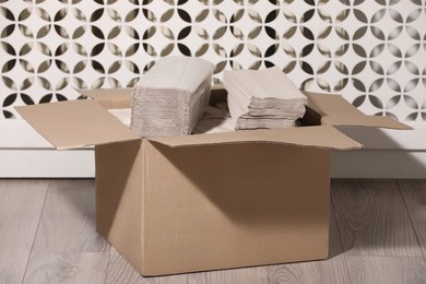 Cardboard box with paper napkins on floor indoors