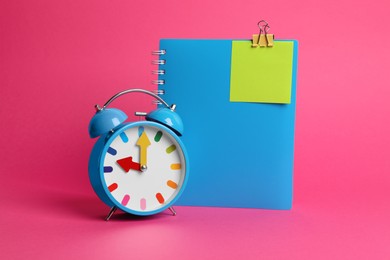 Alarm clock and notebook with blank reminder note on pink background, space for text