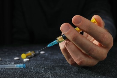 Photo of Drug addiction. Man with syringe on black textured table, closeup and space for text