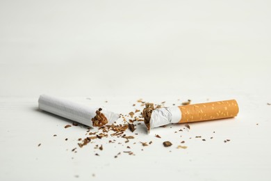 Photo of Broken cigarette on white table, closeup. Quitting smoking concept